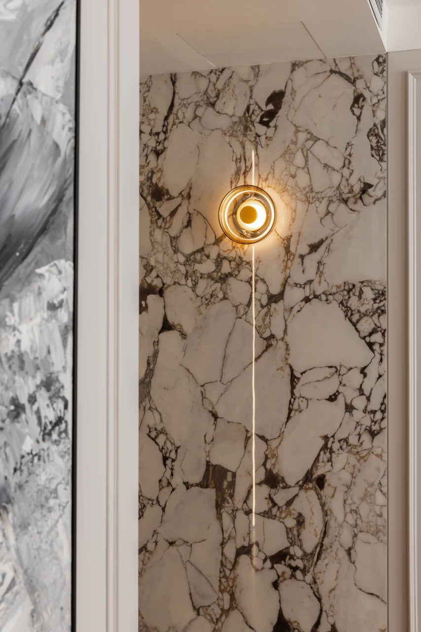 The small brass-toned light against veined stone supplies an intimate punctuation.