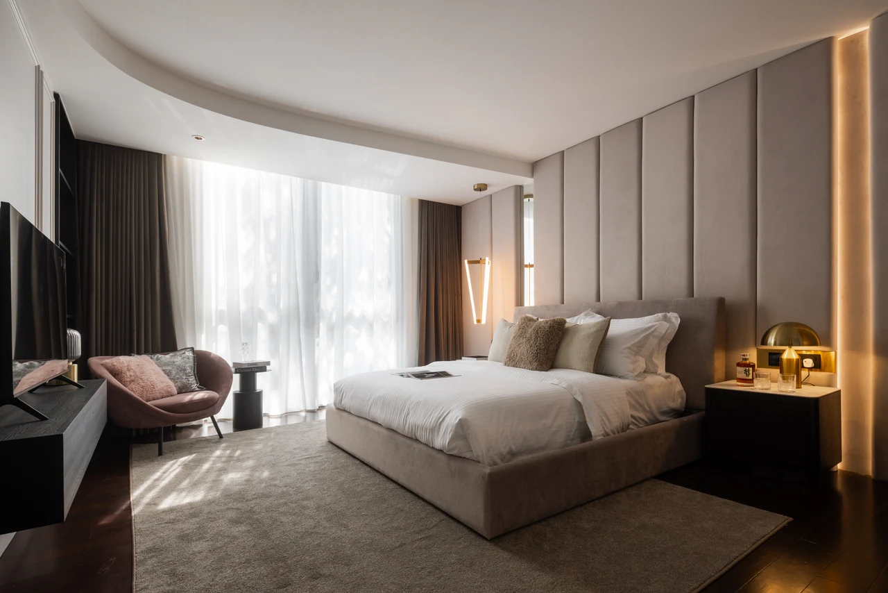 The principal bedroom combines curved ceiling geometry with darker timber and fabric.