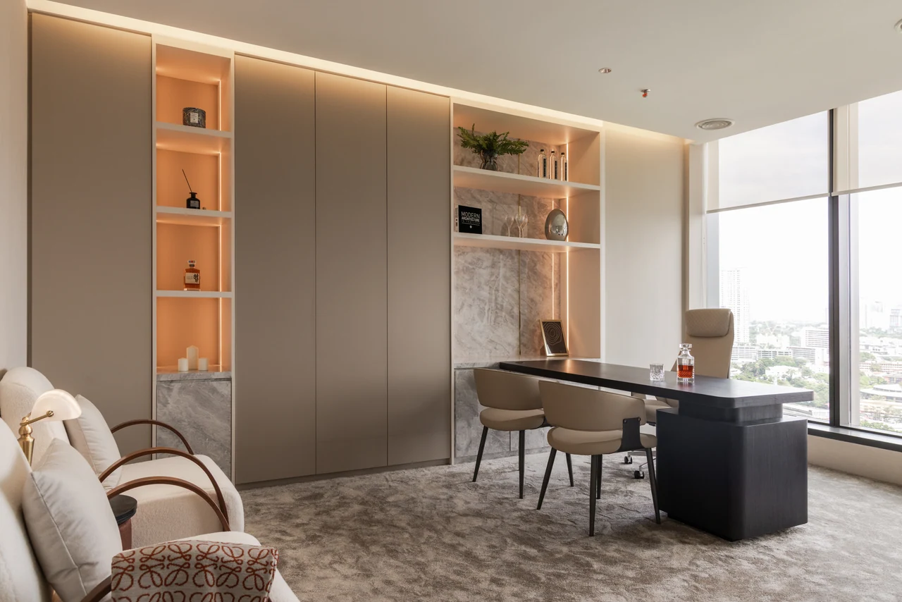 The principal office balances a dark desk with pale cabinetry and warm display lighting.