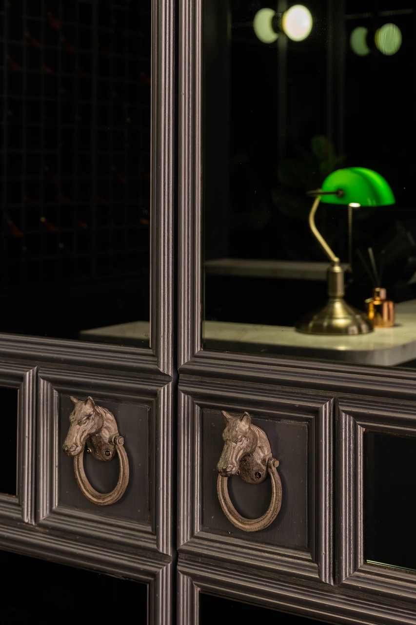 A green-shaded lamp on an ornate dark cabinet