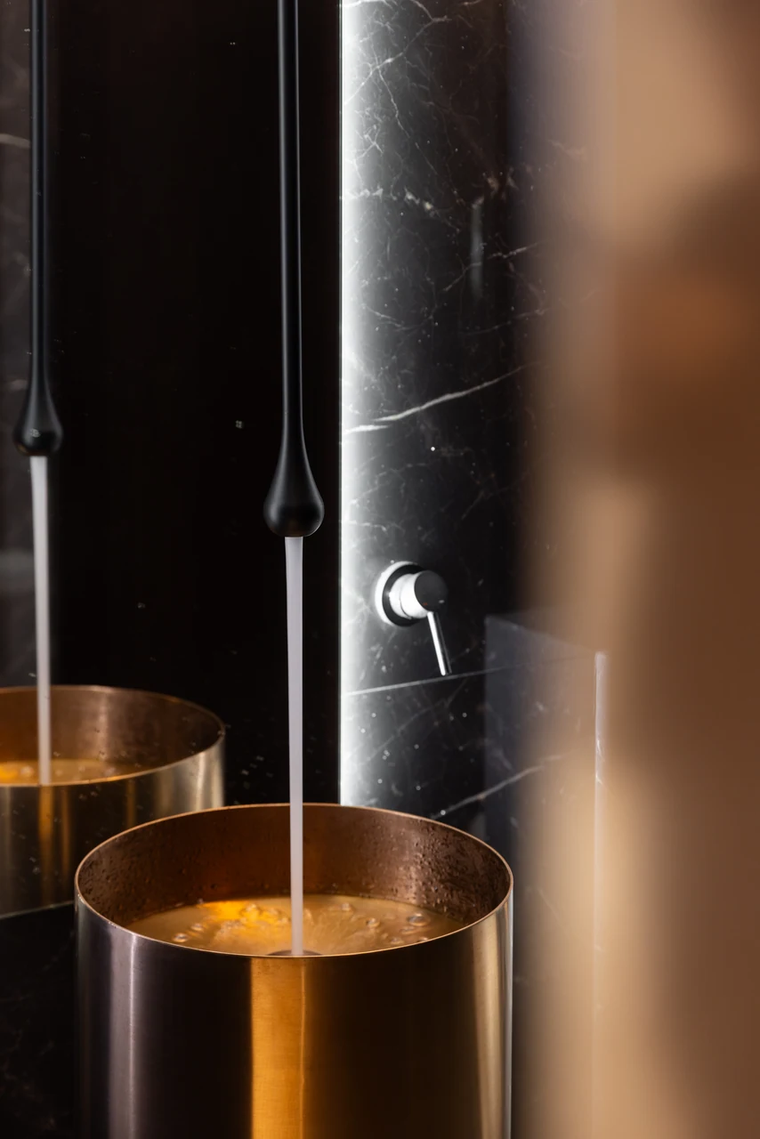 Water entering the brass-toned basin turns the material detail into an experiential image.