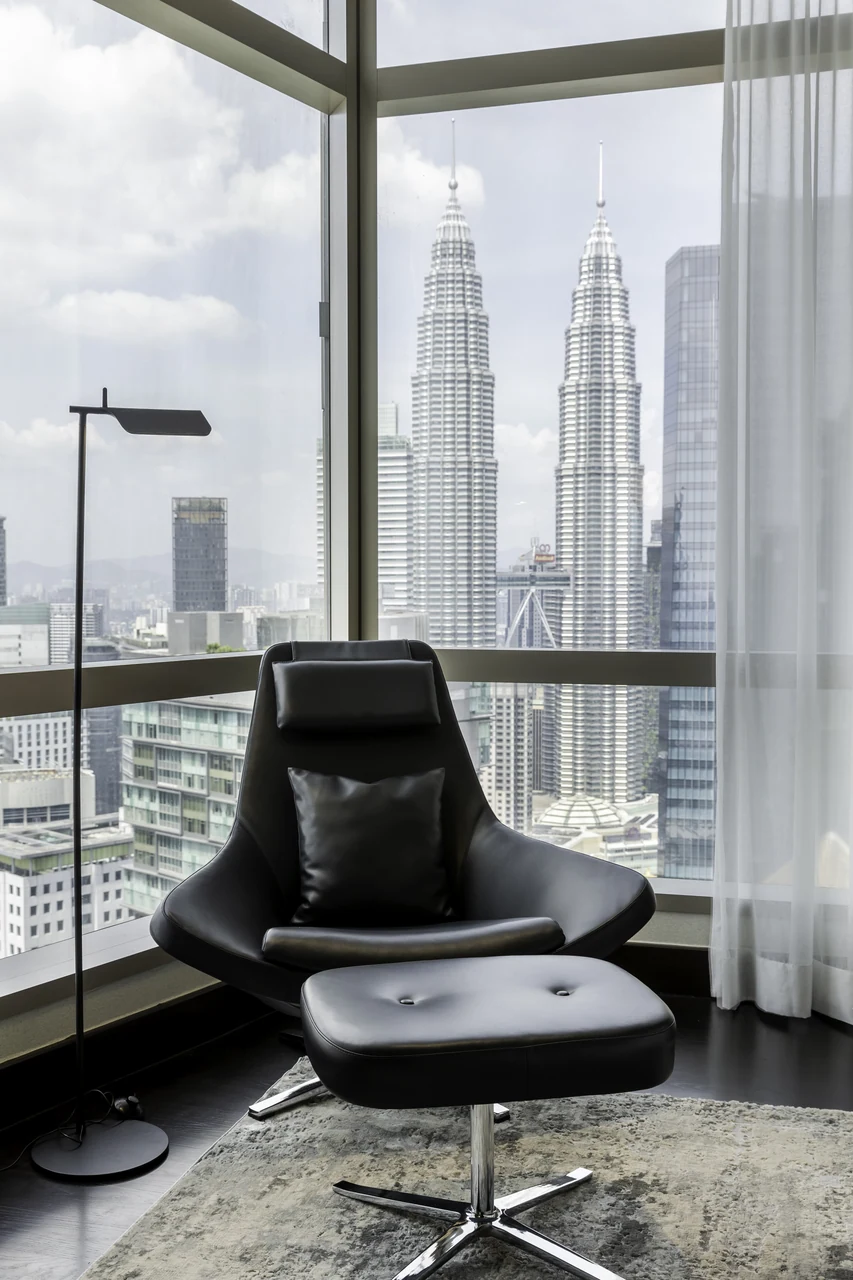 The chair against the Petronas outlook anchors the residence to its location.