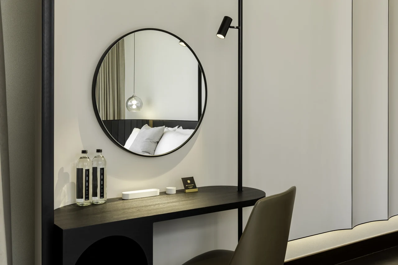 The circular mirror and dark vanity give the bedroom a quiet graphic composition.