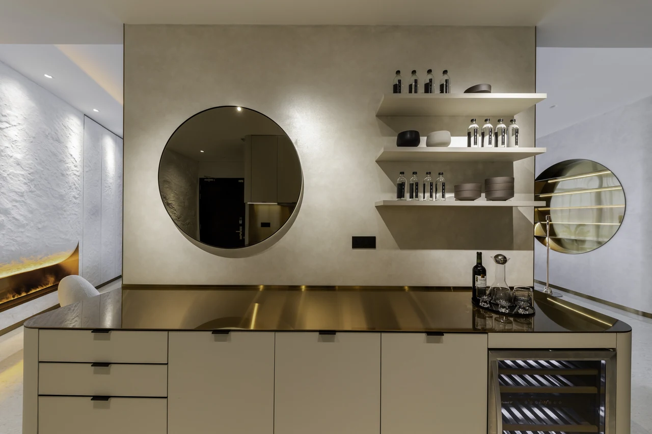 The kitchen’s round mirror, shelving and metallic worktop connect its details into a whole.