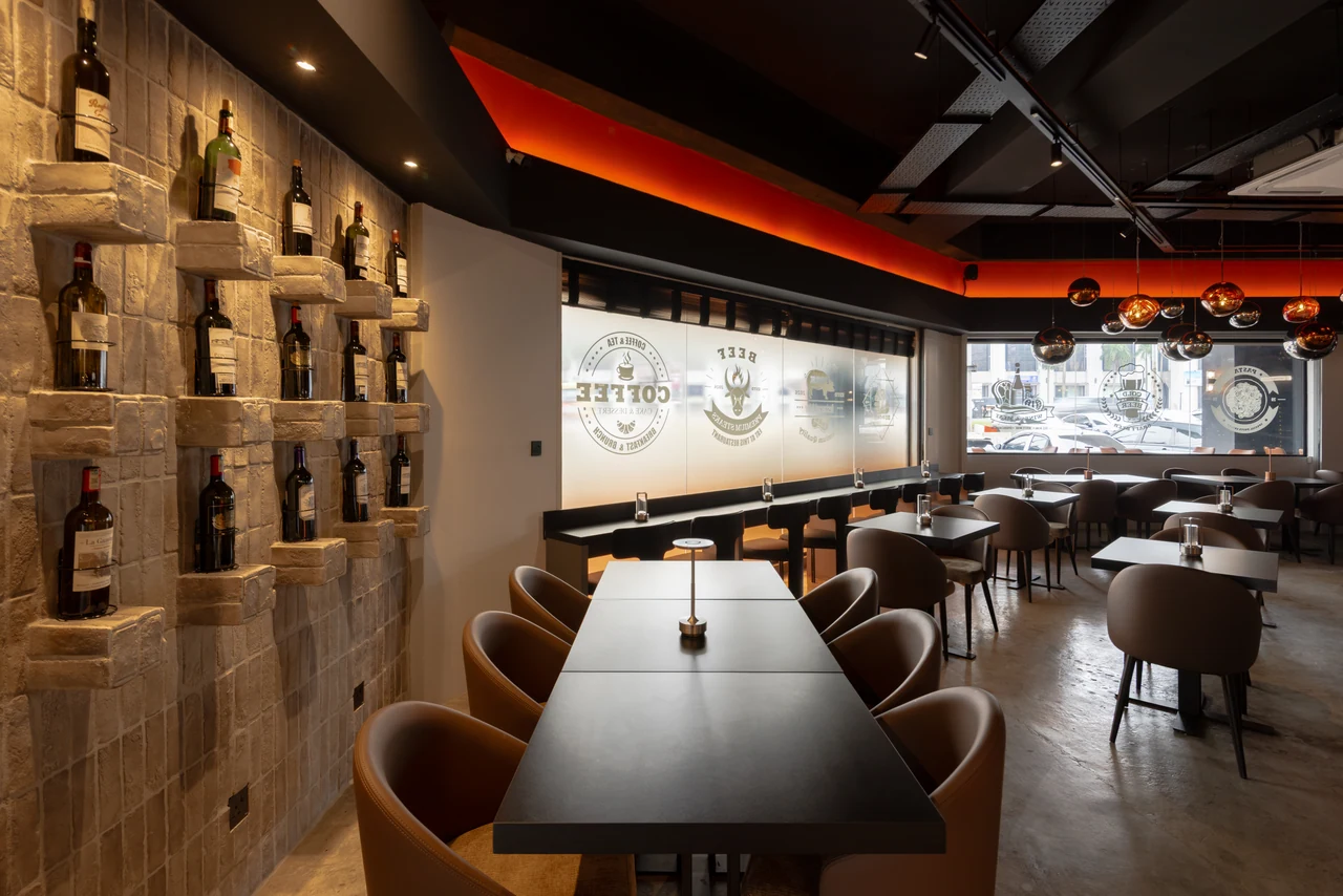 The bottle wall and banquette show the dining experience beyond the central bar.