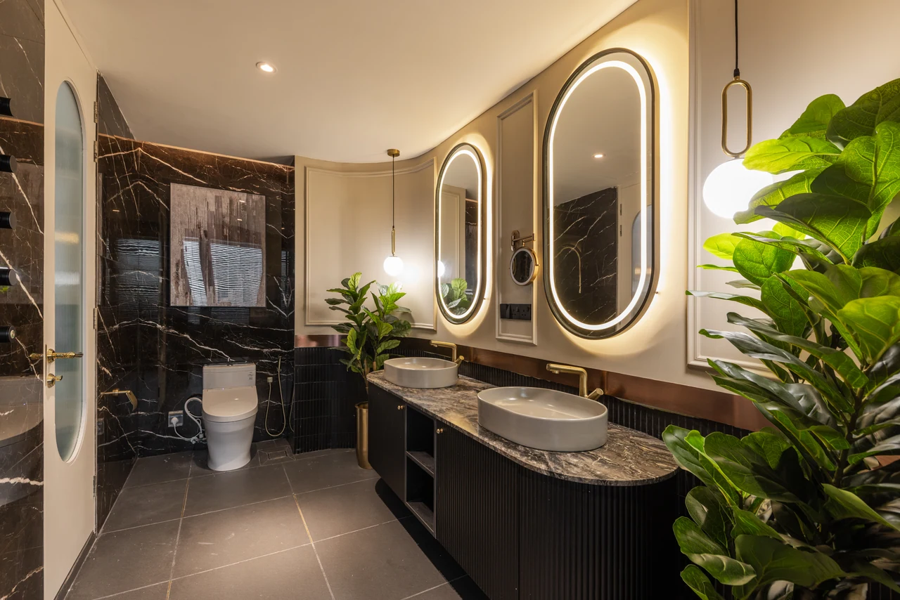 Black stone and illuminated oval mirrors give the bathroom a distinct material chapter.